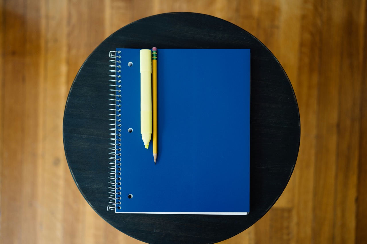 Student taking notes with laptop and books