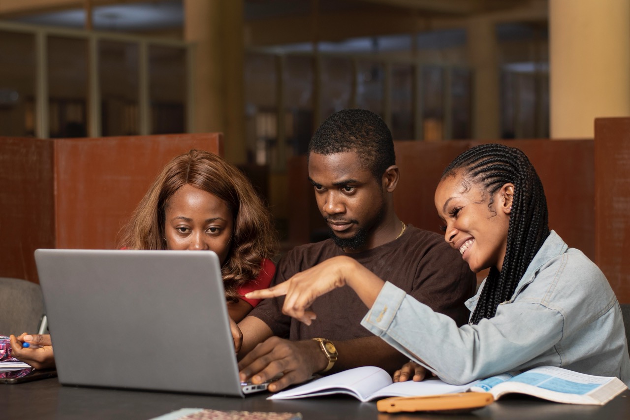 Student taking notes with laptop and books
